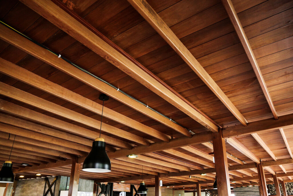 a wooden ceiling with a black light fixture from the ceiling